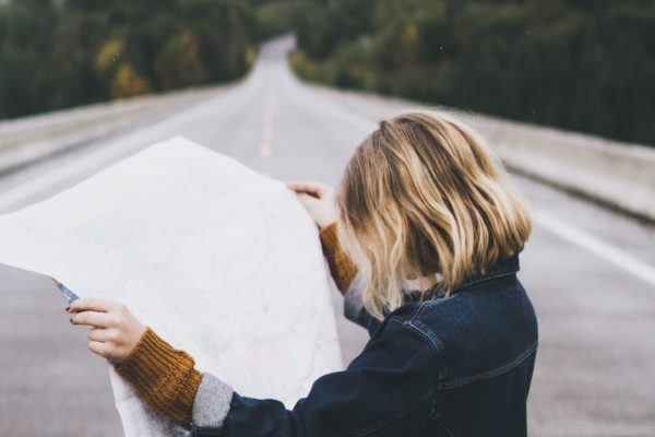 woman looking at map while standing on road